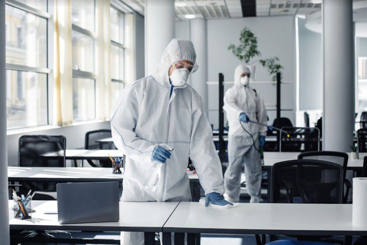 Professional disinfection service team in PPE sanitizing a commercial space